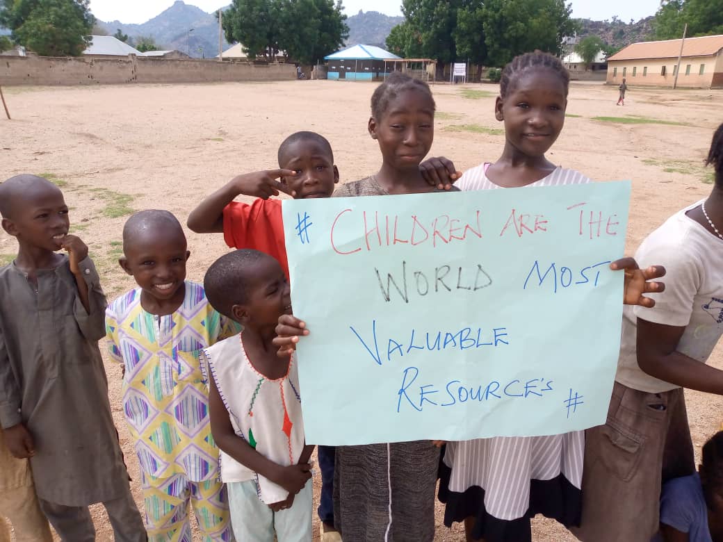 Children holding a handwritten message about the value of children